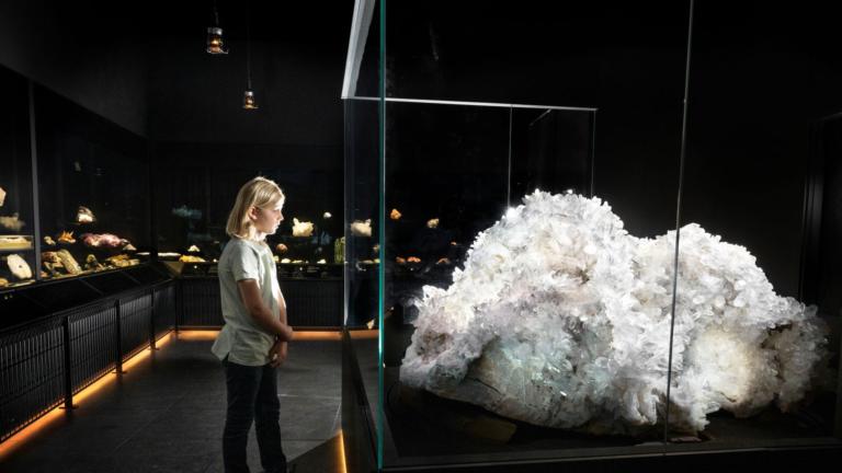 Een jongetje kijkt naar een stuk bergkristal dat groter is dan hijzelf.