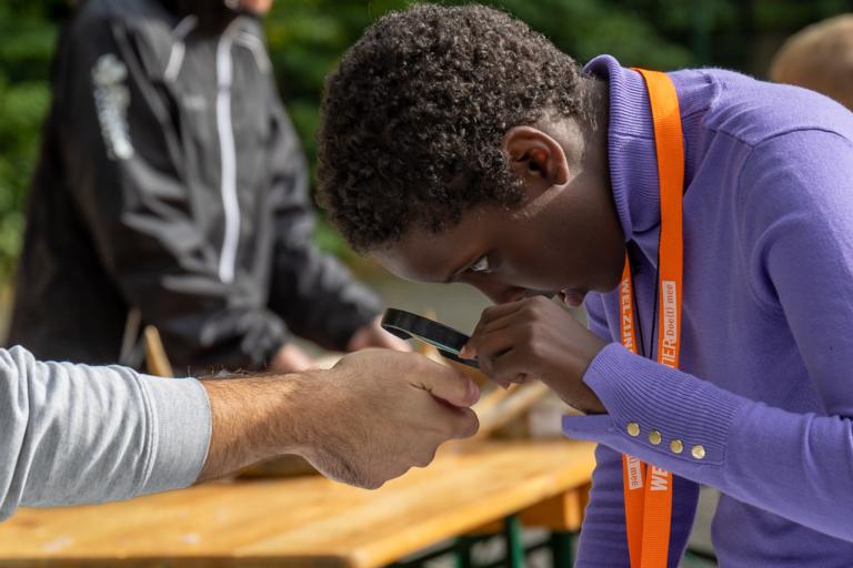 Meisje kijkt door loep naar fossielen